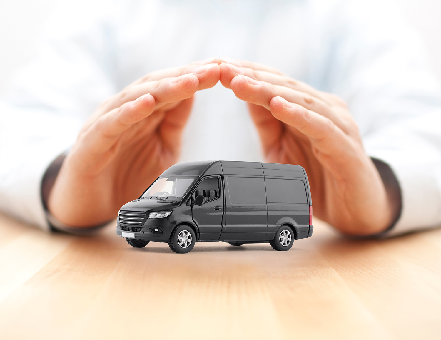 Hands of a man pictured protectively around a very small van