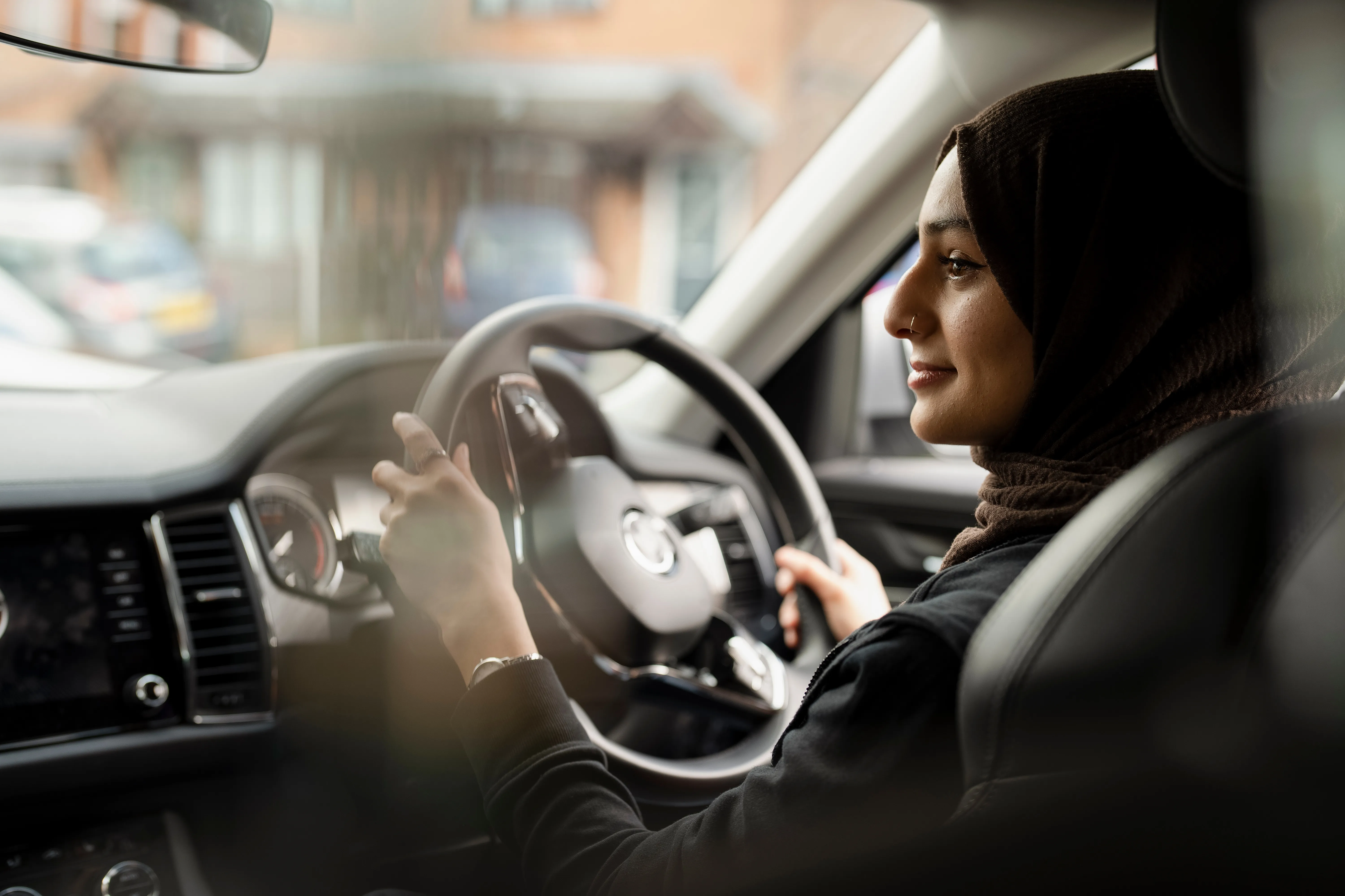 Young woman wearing hijab driving car
