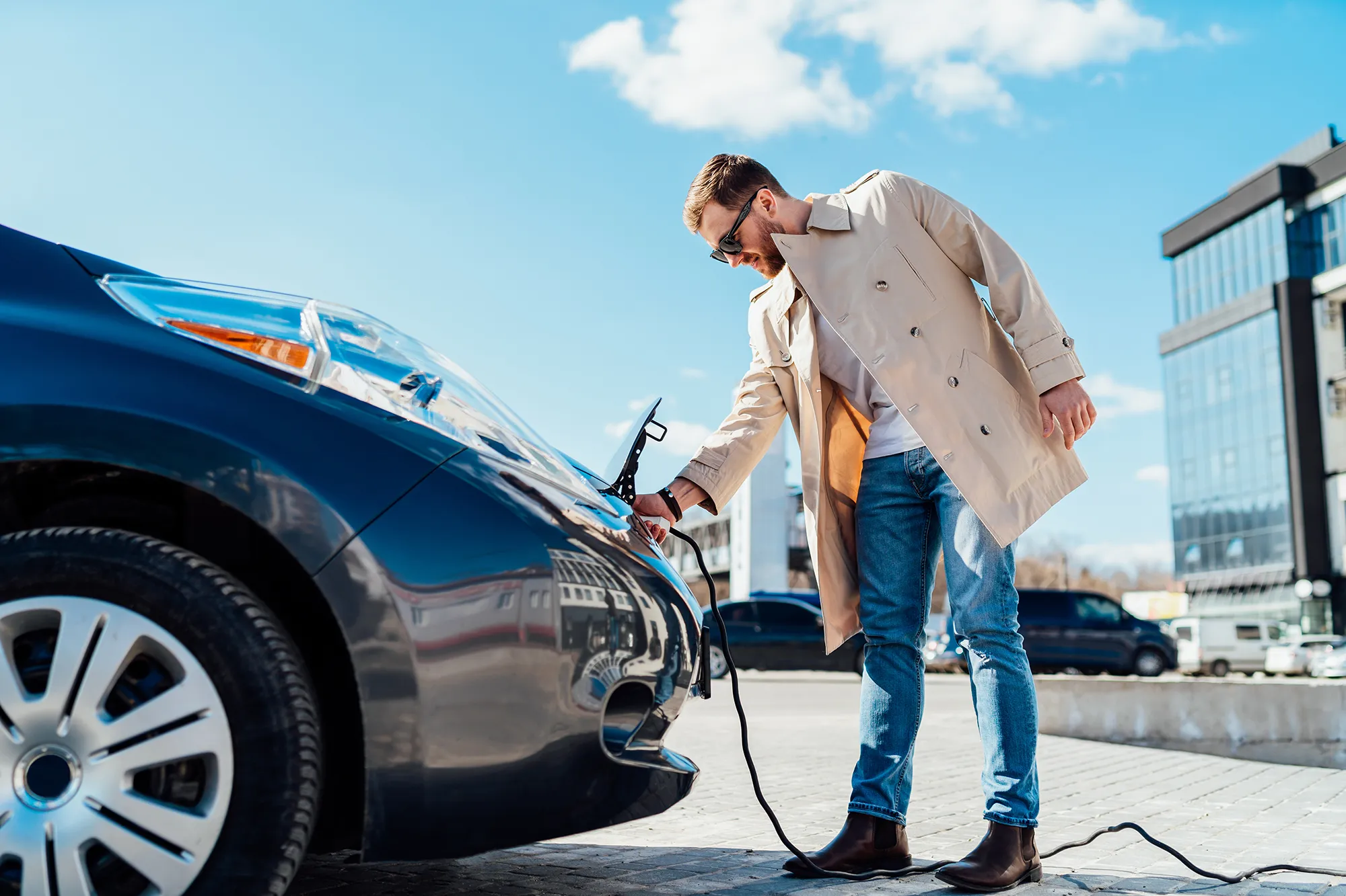 man charging an electric vehicle in a city environment