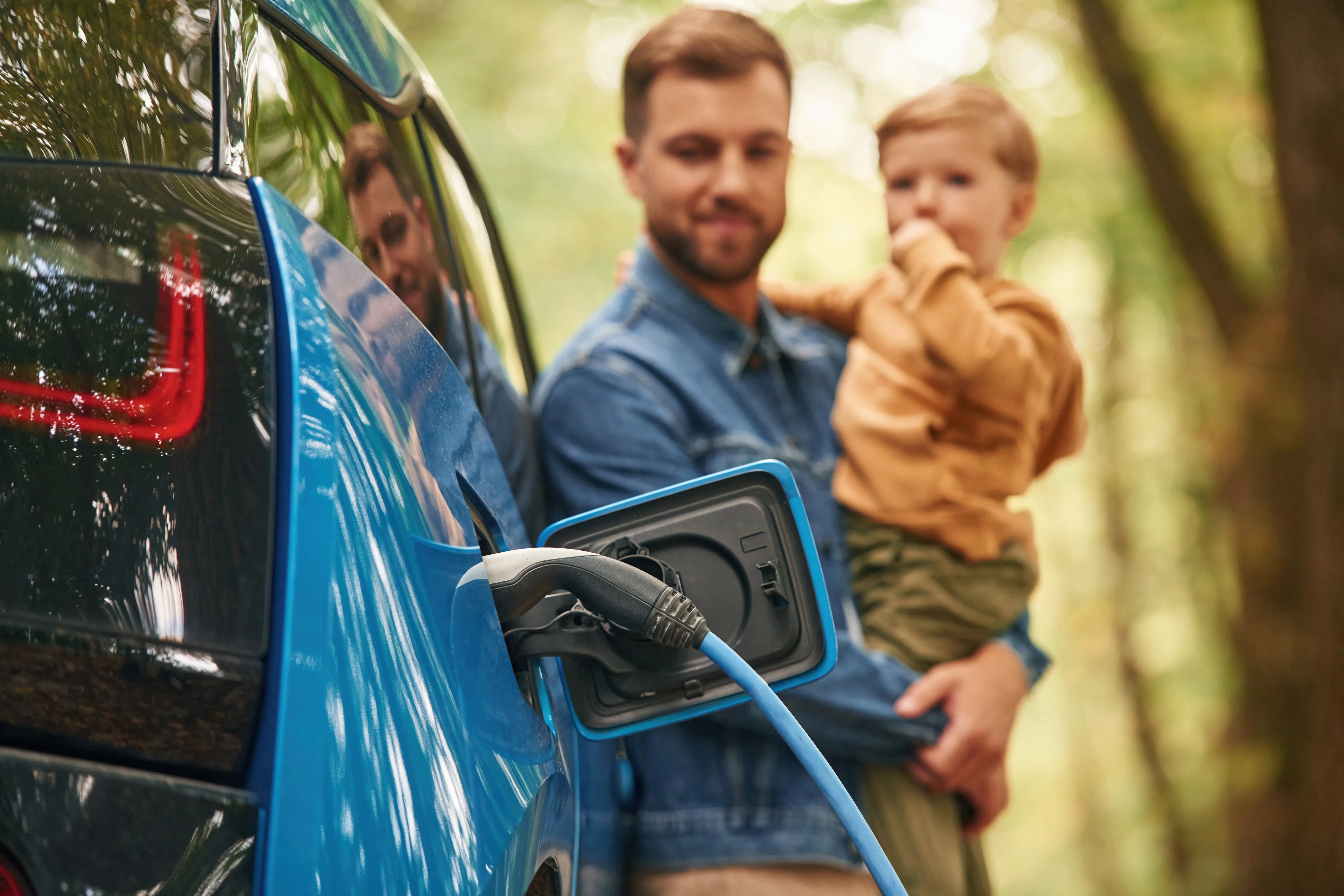 Stock image_Parent and child outside with EV on charge