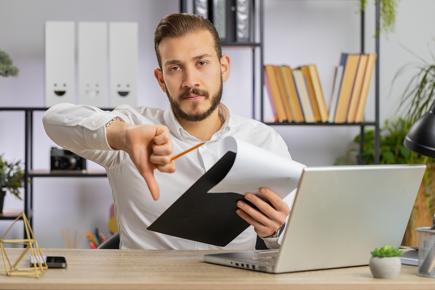 Man with lap top making the thumbs down gesture to signify being told no
